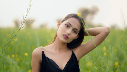 Indian close up young adult gen z model lady woman wear black dress outdoor garden enjoy nature...
