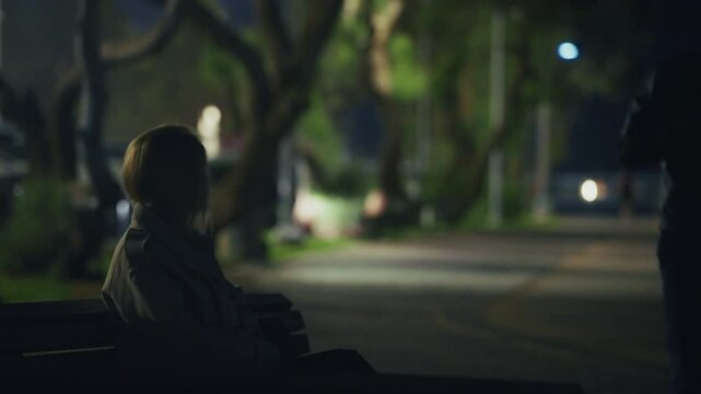 Suspicious package is given to female agent by man in leather jacket in a park. Dark scene at night as two people trade information or pay off debt. Corruption and fraud or conspiracy by government