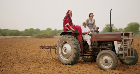 Indian village farmer young woman lady wear red saree smiling sitting on tractor outdoor Asian...