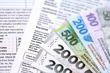 Argentine pesos money bills in big amount lies on table with pen and tax forms close up