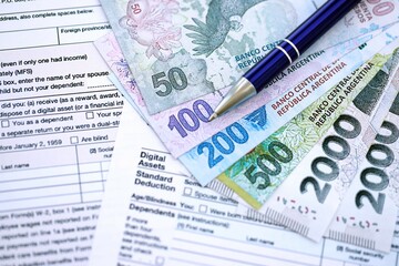 Argentine pesos money bills in big amount lies on table with pen and tax forms close up