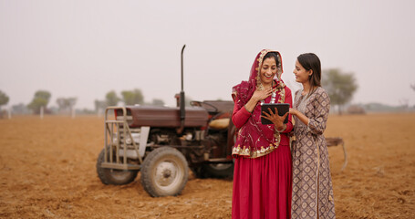 Indian asian villager farmer young adult woman lady wear red saree smiling outdoor hold tab device...