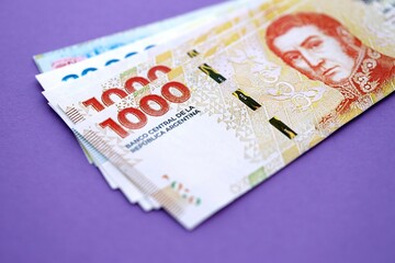 Argentine pesos money bills in big amount lies on purple color table close up