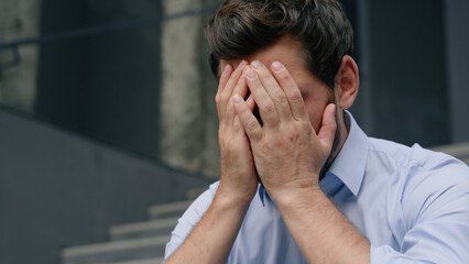 Stressed fired business man upset frustrated grief businessman upset in city middle-aged male entrepreneur suffering holding head headache financial crisis sad thinking close face with hands migraine