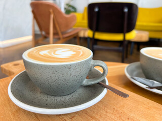 A steaming cappuccino rests on a rustic wooden table in a stylish café, its creamy foam art contrasting with sleek contemporary interiors. Perfect for coffee brands and café lifestyle content.