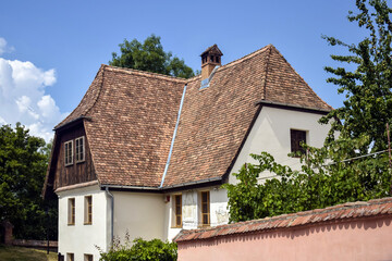 Architectural Details. Attic roof of house made of red tiles with chimney and windows against background of blue sky with clouds. Copy space. Selective focus.
