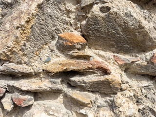 Close-up of weathered stone wall with rough texture and natural colors