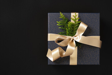The gift box made of elegant dark blue paper is tied with a golden satin ribbon and decorated with...