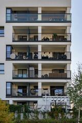 Obraz premium Facade of an apartment building showing the everyday life of its residents on their balconies. Each private balcony is a personalized space with plants, furniture, and bicycles.