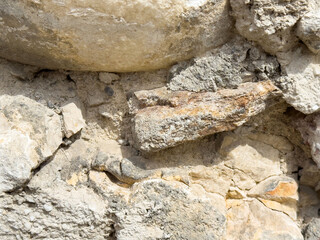 Close-up of rough weathered stone wall with textured surface