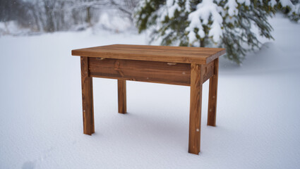 Wooden table sitting in the snow covered outdoors in winter time