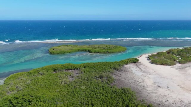 Small Green Island Near La Caobita Beach On A Sunny Day In Azua, Dominican Republic. - aerial shot