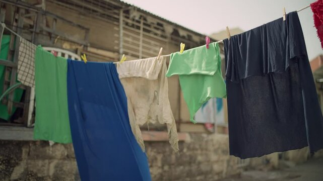 Laundry and fabrics and clothes hang on rope or line in rundown street alley in low income neighborhood or district. Favella or economic crisis in poor area. Hot climate weather as clothes dry in sun