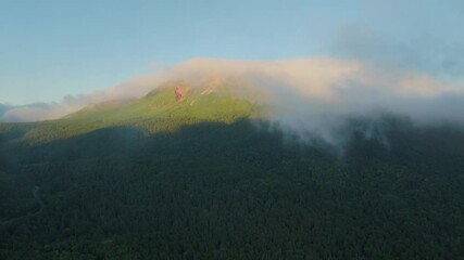Aerial fly through clouds at dawn in Hokkaido’s Onneto forest mountains, Japan landscape reflecting Ainu heritage and summer stillness