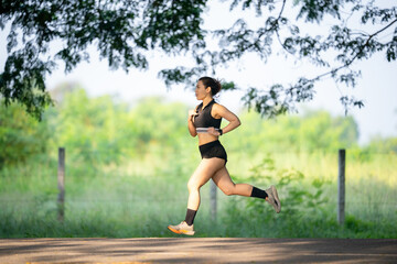 A woman is running on a road. She is wearing a black shirt and black shorts