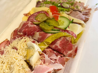 Assorted cold cuts and cheese platter with vegetables and olives