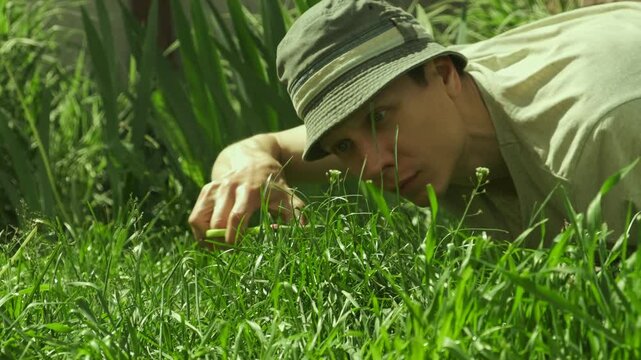 Man bends to cut grass with scissors, mocking lawn perfectionism.
