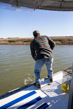 Fisherman throwing a crab trap in the water off a boat 