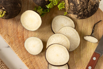 Sliced black radish on wooden cutting board. Top view.