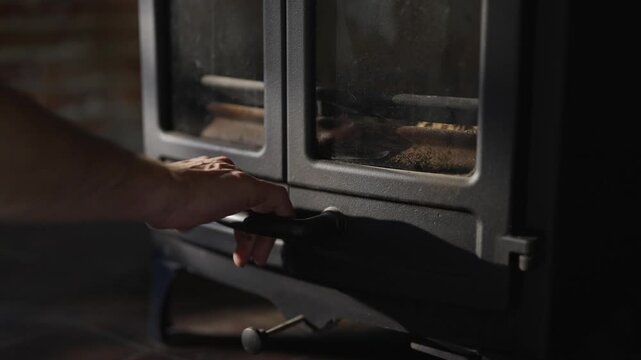 A black stove with a black handle and a glass door. The stove is sitting on a wooden floor
