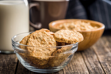 Sweet oatmeal cookies in bowl on wooden table.