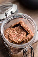 Sweet oatmeal cookies in jar on wooden table.