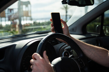 Man driving a car while using a smartphone, representing the danger of distracted driving and lack...