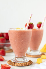 Fruit smoothie with strawberry and mango on table with white background. Close-up. Copy space. Cold...