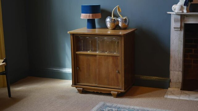 A wooden cabinet with a blue lamp on top of it. The lamp is on a table next to a fireplace