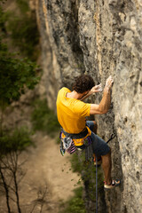 A man in a yellow shirt is climbing a rock wall