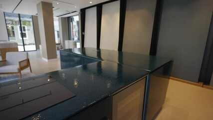A glass counter top with a blue top and a white chair in the background. The counter top is clean and shiny