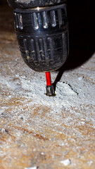 The process of driving a screw into a wooden surface using a cordless screwdriver. Woodworking:...