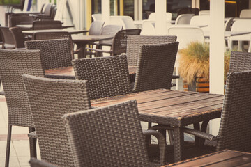 Chairs made of wicker or rattan and tables on restaurant terrace. Relaxation time on fresh air