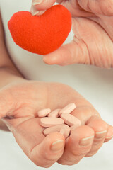 Hand of senior woman with tablets, vitamins or supplements and heart. Treatment or strengthening immunity in old age