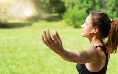 Fit woman meditating outdoors with mudra hand gesture enjoying music with wireless earphones