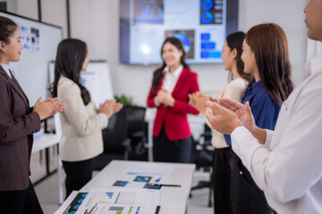 Fototapeta premium A group of women are clapping and smiling at each other in a conference room