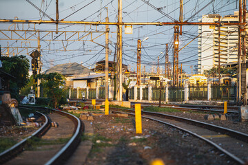 Train tracks and overhead power lines in an urban setting during sunset.