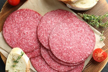 Slices of tasty smoked sausage, tomato, thyme and bread on table, top view