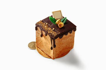 Delicious mini cake with chocolate icing and gold flakes on white background