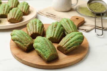 Tasty matcha madeleine cakes on white marble table, closeup