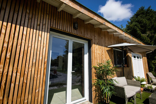une petite maison moderne vu de l'ext&eacute;rieur les murs sont en bardage bois, le ciel est bleu