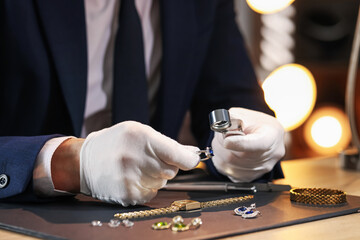 Appraiser with loupe evaluating ring at table indoors, closeup
