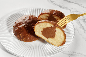Fork taking a slice of chocolate-covered cake filled with chocolate cream