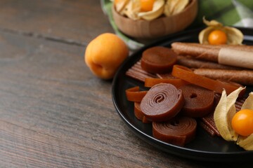 Tasty fruit leather, physalis and apricots on wooden table, closeup. Space for text