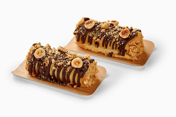 Two hazelnut and chocolate covered mini cakes resting on cardboard trays