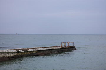 Seascape of distant group of seagulls rest on the metal railings of an old concrete sea pier