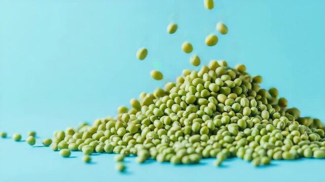 Pile of green mung beans with falling grains on blue background