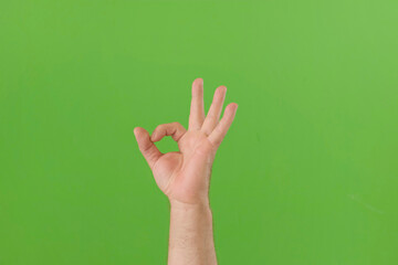 Male Hand Making OK Sign with Fingers. Man Fist Showing Victory Symbol Gesture Isolated against Chroma Key Green Screen Background. Body Language. 4K Footage. Close Up. Everything is Good. Proposing
