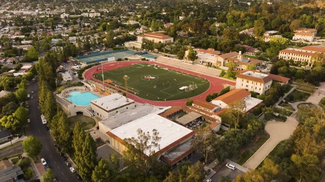 drone of a track and field athletic stadium with a pool, tennis courts, and soccer field on a small college campus in Los Angeles on a warm day overlooking mountains in the distance
