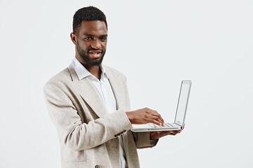 Professional confident man holding a laptop computer, wearing a beige blazer and white shirt,...
